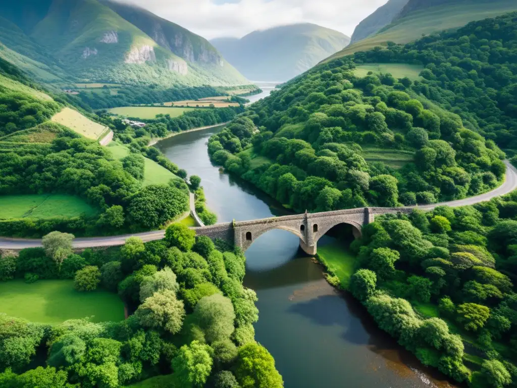 Un antiguo puente de piedra documentado con drones se extiende sobre un río, rodeado de exuberante vegetación y montañas escarpadas