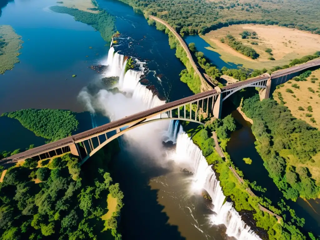 Vista aérea del icónico Puente de las Cataratas Victoria sobre el río Zambeze, destacando su estructura de acero frente a la majestuosa cascada y exuberante paisaje